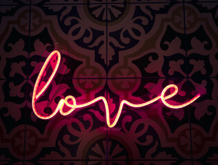 Love. Neon sign letter word Love in bright red colours glow in the dark on pattern tiles wall...