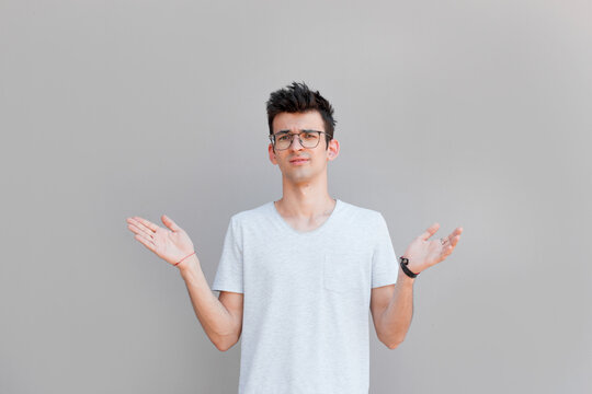 Closeup portrait of dumb clueless young man, arms out asking what's the problem who cares so what, I don't know. Isolated on white background. Negative human emotion, facial expressions, attitude