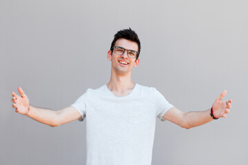 Free hugs for person who had bad day. Cheerfull kind male model in white t-shirt, pulling hands towards camera, wanting to cuddle, smiling broadly, welcoming friend to come into his arms