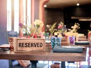 Wooden reserved sign on dining table in restaurant.