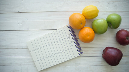 Top view set of raw food with a notebook on white wooden background. Healthy food concept