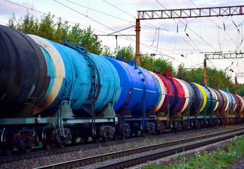Fototapeta na wymiar Freight train with petroleum tank cars on railroad. Rail cars carry oil and ethanol. Railway logistics explosive cargo. Transportation of methanol, crude and gas. Petrochemical tank cars. Out of focus