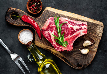 Raw cowboy steak. Marbled beef meat 
with spices on a stone background
