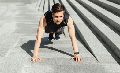 Outdoor sport. Man in sportswear with smart watch, push ups at stairs