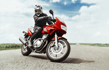 A man rides a motorcycle on the highway to the camera. A man on a red motorcycle makes a turn in...