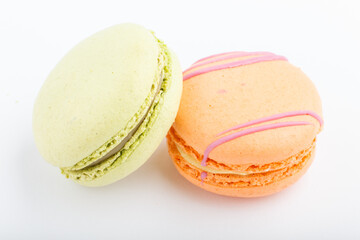 Orange and green macarons or macaroons cakes isolated on white background,  side view.