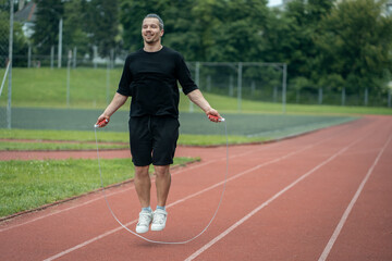 Fototapeta premium young athlete has workout and jumps on skipping rope outdoor