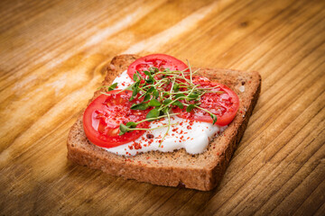 Healthy sandwich with cream cheese, microgreens and tomato slices and spices on cutting board. Healthy eating, diet vegan food. Top view.