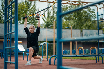 young sporty athlete or bodybuilder has fitness workout with trx outdoor