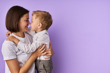 tender caucasian child boy touches the nose of mother, lovely mother makes child happy, give...