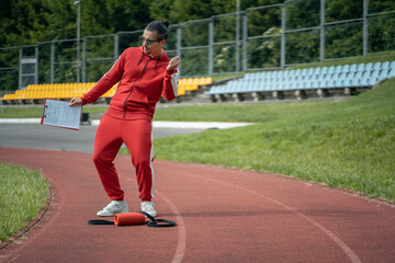 Obraz premium young cheerful personal fitness trainer at running track and with tablet