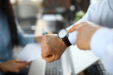 Man in office shows a finger at clock. Improving work efficiency during working hours concept