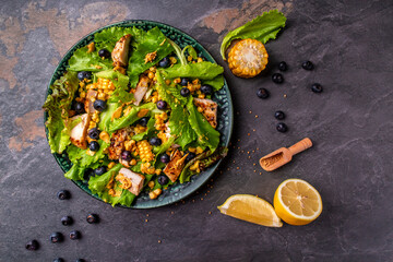 Fresh salad with chicken breast, corn, lemon, mustard and blueberries. Top view