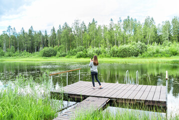 girl using smart phone by the lake in the forest