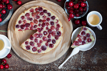 Tart with ripe sweet cherries and green tea on brown background. Homemade dessert with ripe sweet cherries. Top view