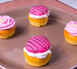 Several colorfully decorated cupcakes on a brown plate, side view