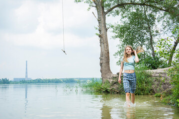 In the summer afternoon, a teenager girl stands in a lake.