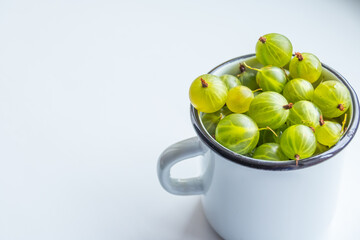 Fresh organic Gooseberries in a metal cup. Fruit background,copy space. Summer berries harvest concept. Vegan, vegetarian, raw food.Green gooseberry on white background. Sweet,juicy berry.
