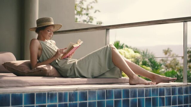 Young attractive girl reads a book outdoors