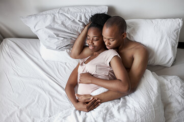 young black african couple sleeping sweetly together at home, man hugs his pregnant wife, in love