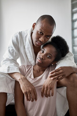 portrait of beautiful african black couple at home, man and woman posing at camera, sit on bed. in love