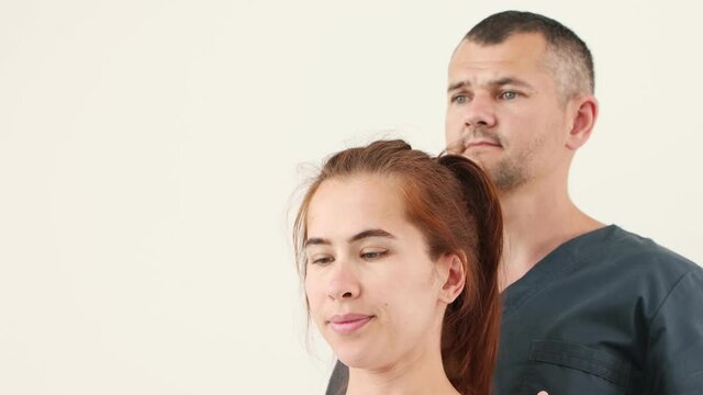 Massagist holding young woman's neck in certain position