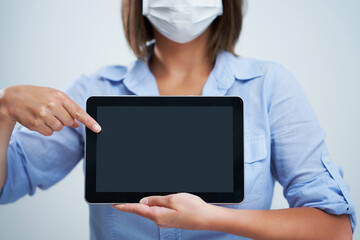 Woman wearing protective mask and holding tablet isolated over white background