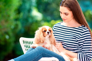 Happy young woman with her cavalier puppy sitting outdoor