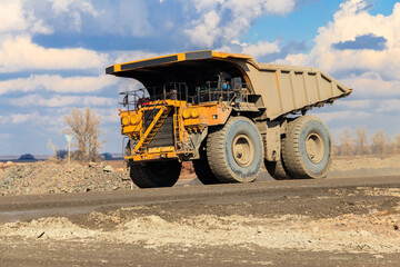 Huge yellow mining dump truck working in iron ore quarry. Mining industry