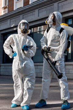 brave professional disinfectors in protective hazmat suit walking through city streets and spraying disinfectant to stop spreading highly contagious coronavirus or COVID-19, use special equipment