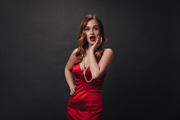 Fototapeta premium Nice woman in red elegant dress surprised looking into camera
