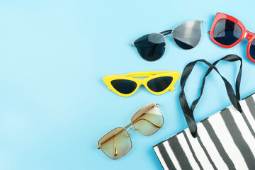 color fashion sunglasses and paper bag arranged on blue background with copy space,shopping concept