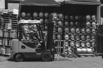 Fototapeta na wymiar Metal barrel. Keg with beer. A large number. Stock. Logistics and alcohol concept. Wooden pallets. Black and white. Car loader