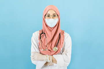 Smart young muslim woman doctor in lab coat with Medical face mask,white latex medical gloves and stethoscope against blue background,health care concept