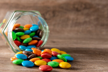lentejas de chocolate en un frasco sobre un fondo de madera con foco selectivo