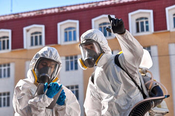 professional cleaning and disinfection at town complex amid the coronavirus epidemic. two workers prevent and control epidemic. in protective suit and mask