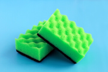 dishwashing sponge. two green sponges for washing dishes and other surfaces on a blue background. cleaning concept