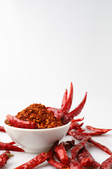 Cayenne pepper in a white cup with many red dried chilies.
