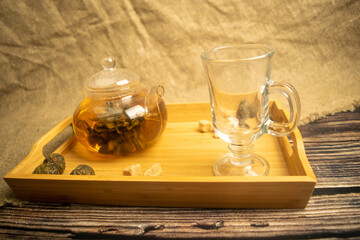 Flower tea brewed in a glass teapot on a wooden tray. Close up.