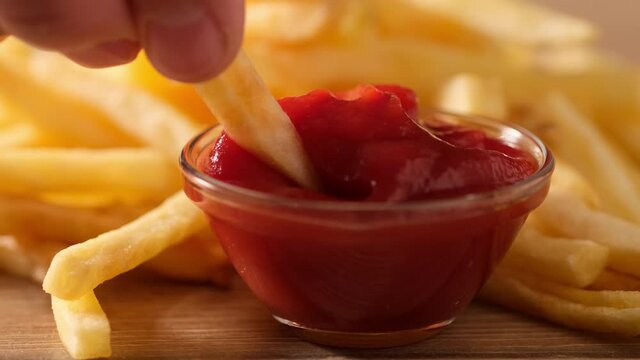 Hand grab french fried and dip into ketchup Close up