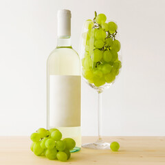 Bottle of white wine with anonymous label and a large and transparent glass goblet filled with...