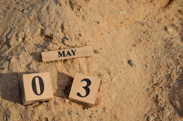 May 3, Number cube with Sand pile for a background.