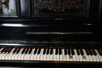 old black piano with copper candlesticks against a brick wall