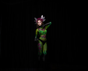 beautiful girl painted with green paint and flowers on her face and burgundy peonies in her body posing in different poses