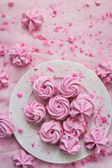 Pink meringues on plate, colorful background, top view