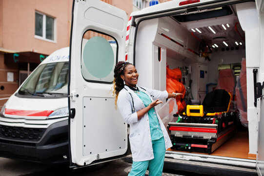 African american female paramedic standing in front of ambulance car.