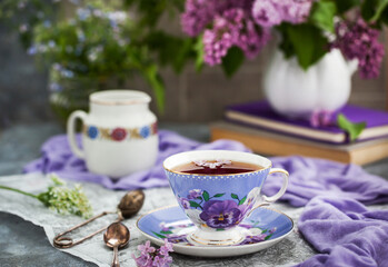 Purple cup of tea and lilac on gray background