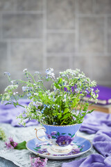 Bouquet of forget-me-nots in ceramic cup on a light gray background