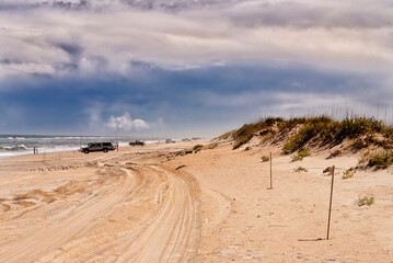 Vehicles parked on the beach leaving tire tracks in the sand at Outer Banks, North Carolina.
