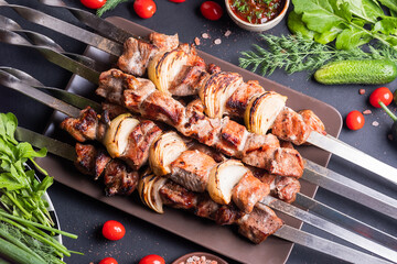Fresh, home-cooked on the grill fire meat beef shish kebab with vegetables and spices, with barbecue sauce and ketchup, on a dark background. Shish kebabs - grilled meat and vegetables
Lamb Skewers